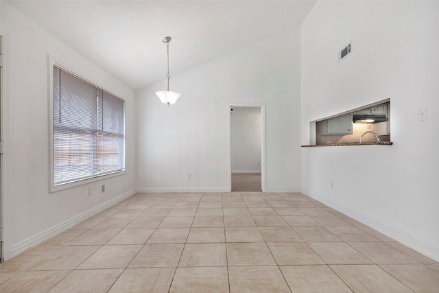 tiled empty room featuring lofted ceiling