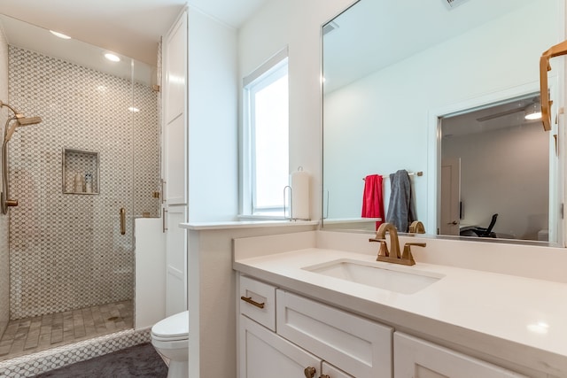 bathroom featuring vanity, a shower with shower door, and toilet