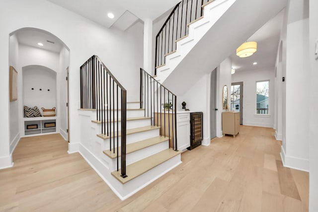 staircase with hardwood / wood-style flooring, a towering ceiling, and wine cooler