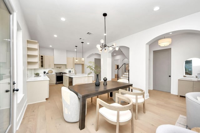 dining room with sink, light hardwood / wood-style flooring, and a chandelier