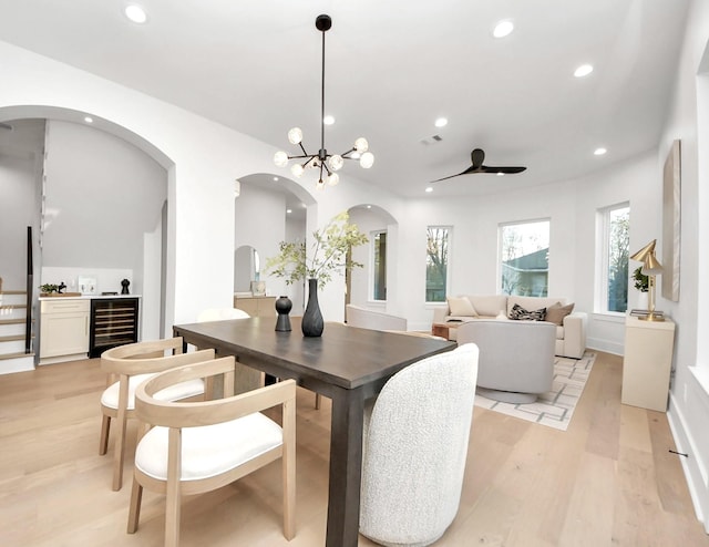 dining area featuring an inviting chandelier, beverage cooler, and light wood-type flooring