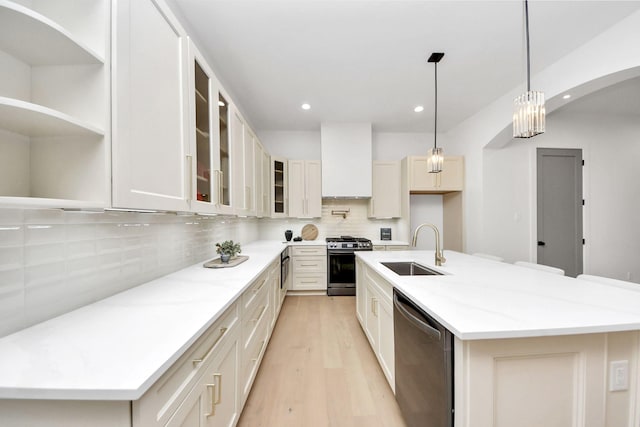 kitchen featuring stainless steel appliances, sink, a center island with sink, and wall chimney exhaust hood