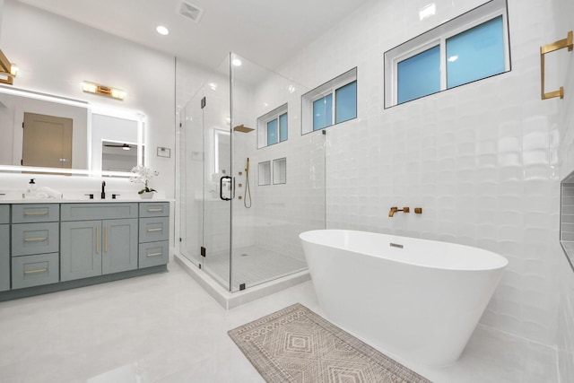 bathroom featuring shower with separate bathtub, tile walls, vanity, and tile patterned floors