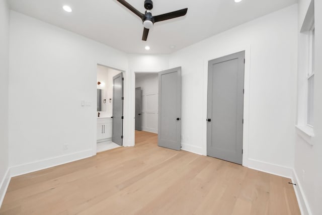 unfurnished bedroom with ceiling fan, two closets, connected bathroom, and light wood-type flooring