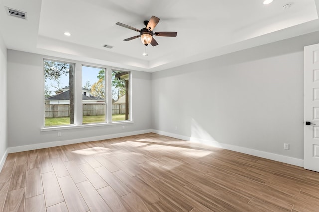 spare room with ceiling fan and a tray ceiling