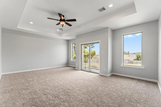 unfurnished room featuring ceiling fan, carpet floors, and a tray ceiling