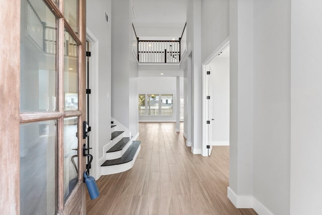 corridor featuring light hardwood / wood-style floors and a high ceiling