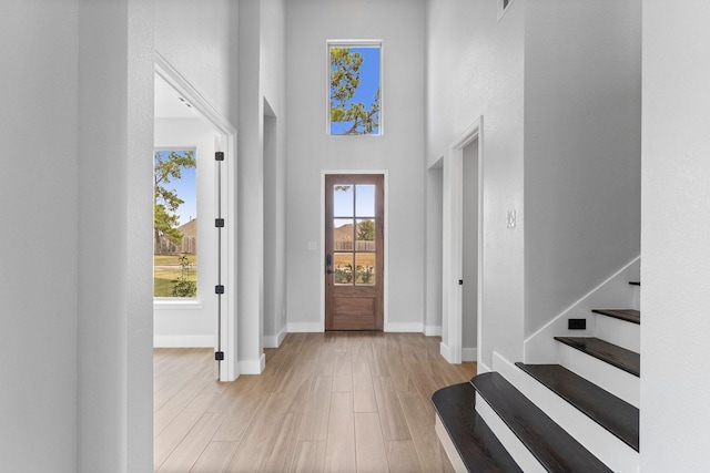 foyer entrance with a towering ceiling and light wood-type flooring