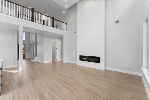 unfurnished living room with a fireplace and a high ceiling