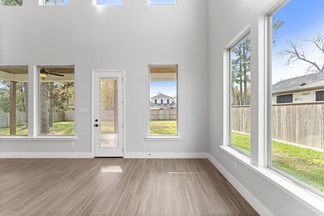 interior space featuring ceiling fan, hardwood / wood-style floors, and a towering ceiling