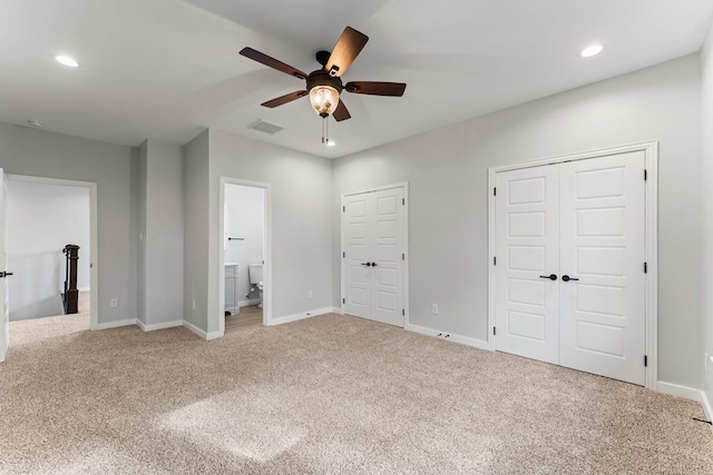 unfurnished bedroom with ceiling fan, two closets, connected bathroom, and carpet floors