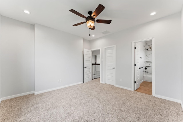 unfurnished bedroom with ceiling fan, ensuite bathroom, and light colored carpet