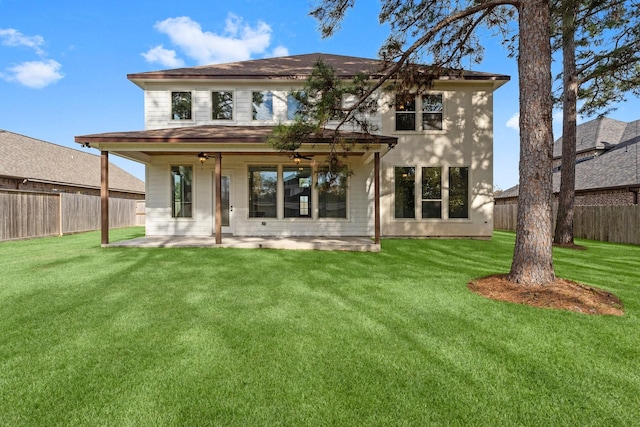 rear view of property featuring ceiling fan, a lawn, and a patio