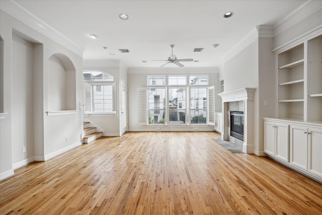 unfurnished living room with ceiling fan, light hardwood / wood-style floors, a tile fireplace, and ornamental molding