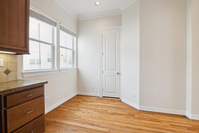 unfurnished dining area featuring crown molding and light hardwood / wood-style flooring