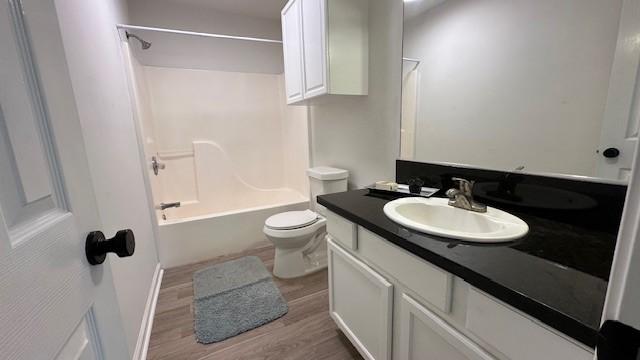 full bathroom with hardwood / wood-style floors, toilet, vanity, and shower / washtub combination