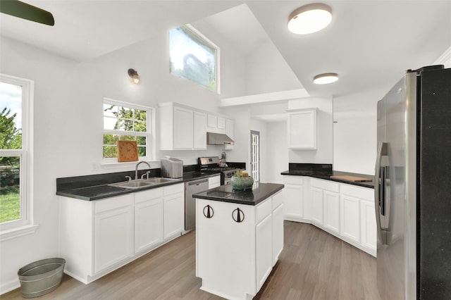 kitchen featuring a center island, white cabinetry, stainless steel appliances, sink, and light wood-type flooring