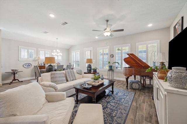 living room featuring ceiling fan with notable chandelier, wood-type flooring, and vaulted ceiling