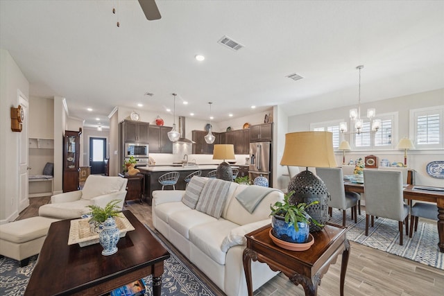 living room with sink, ceiling fan with notable chandelier, and light wood-type flooring