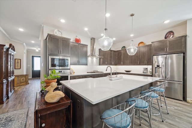 kitchen with wall chimney exhaust hood, dark brown cabinetry, stainless steel appliances, and hanging light fixtures