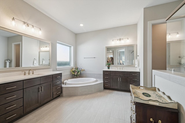 bathroom with a relaxing tiled tub, vanity, and tile patterned flooring