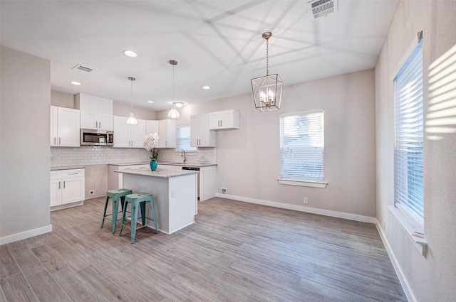 kitchen featuring white cabinets, a kitchen bar, pendant lighting, and a center island