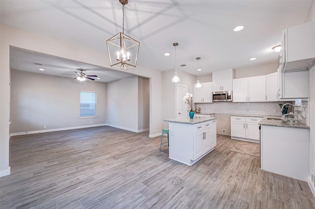 kitchen with hanging light fixtures, backsplash, white cabinetry, and a kitchen island