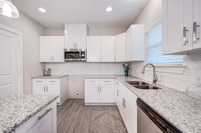 kitchen with sink, white cabinets, appliances with stainless steel finishes, and light wood-type flooring