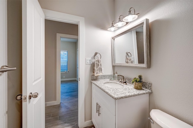 bathroom featuring toilet, hardwood / wood-style floors, and vanity