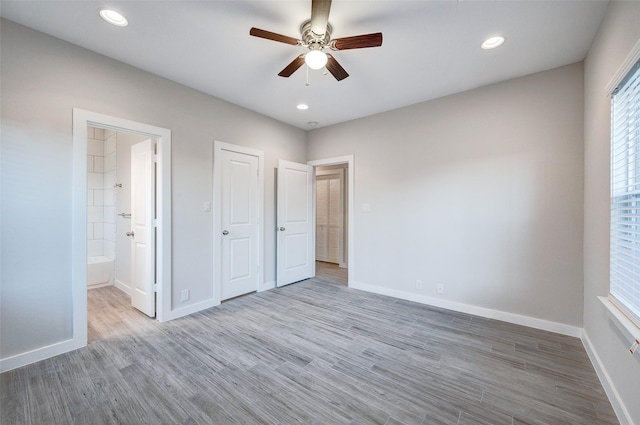 unfurnished bedroom featuring ceiling fan, wood-type flooring, and connected bathroom