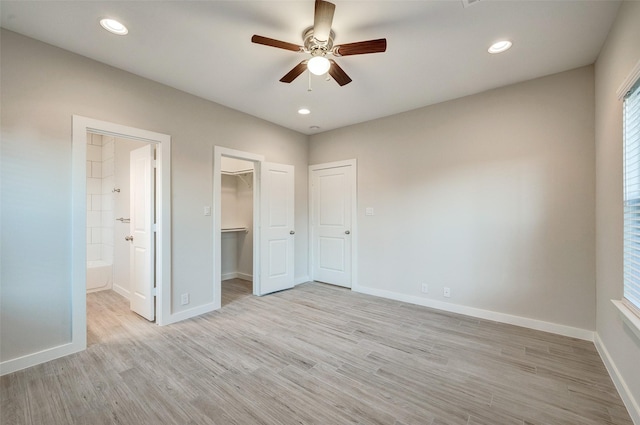 unfurnished bedroom with ceiling fan, ensuite bathroom, light hardwood / wood-style floors, a spacious closet, and a closet