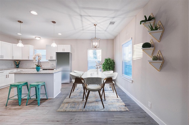 dining room featuring light wood-type flooring, a chandelier, and a healthy amount of sunlight