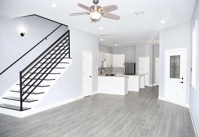 unfurnished living room with ceiling fan, sink, and hardwood / wood-style floors