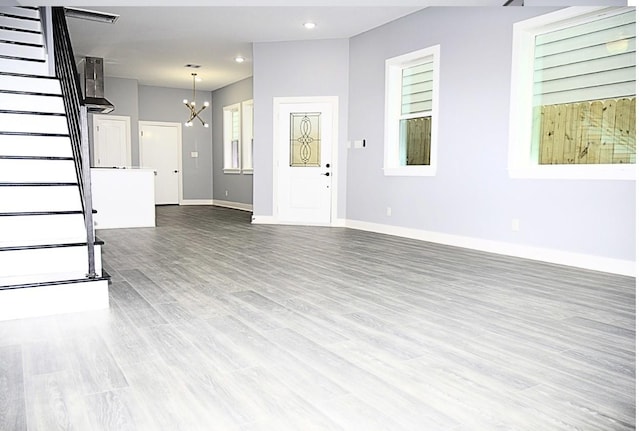 unfurnished living room with a notable chandelier and hardwood / wood-style floors