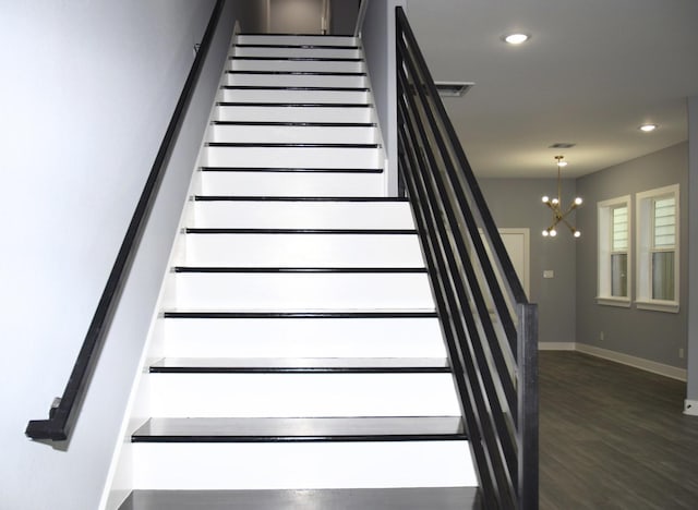 staircase featuring hardwood / wood-style flooring and a notable chandelier