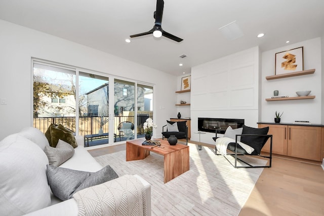 living room with light hardwood / wood-style flooring, a fireplace, and ceiling fan