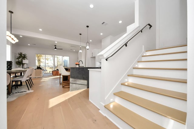 staircase featuring wood-type flooring and ceiling fan