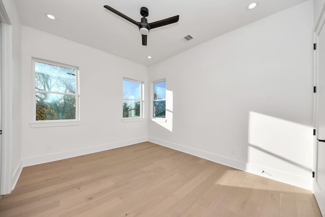 spare room with ceiling fan, a wealth of natural light, and light wood-type flooring