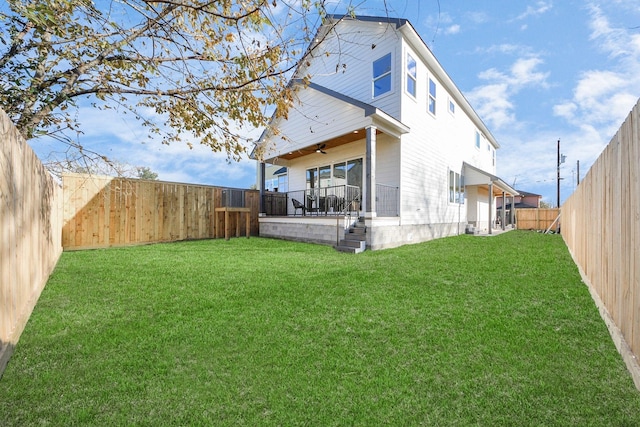 rear view of property featuring ceiling fan and a yard