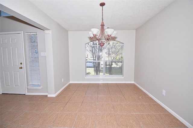 unfurnished dining area with an inviting chandelier, tile patterned flooring, and a textured ceiling