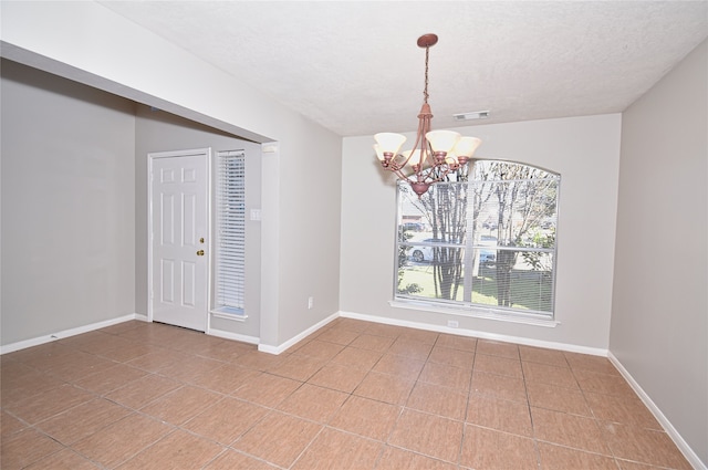 empty room featuring an inviting chandelier and tile patterned floors