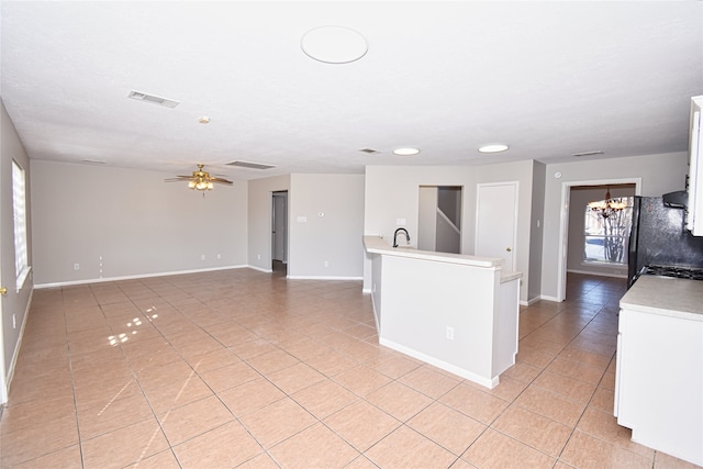 kitchen featuring black fridge, white cabinetry, ceiling fan with notable chandelier, and stove