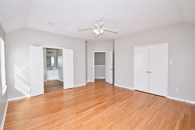 unfurnished bedroom with lofted ceiling, ceiling fan, ensuite bathroom, a closet, and light wood-type flooring