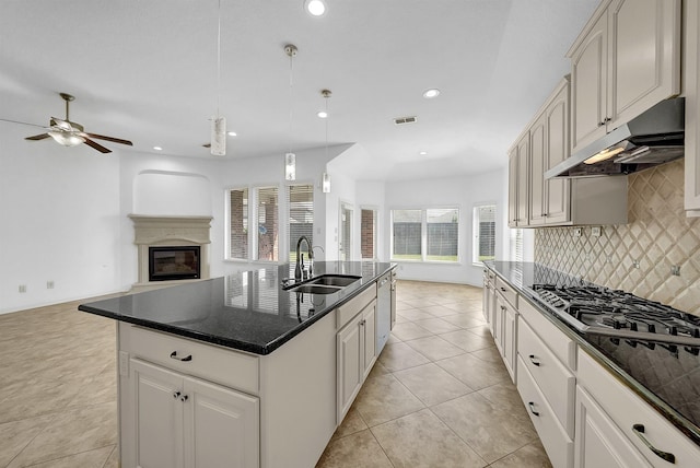 kitchen featuring stainless steel appliances, hanging light fixtures, light tile patterned floors, sink, and an island with sink