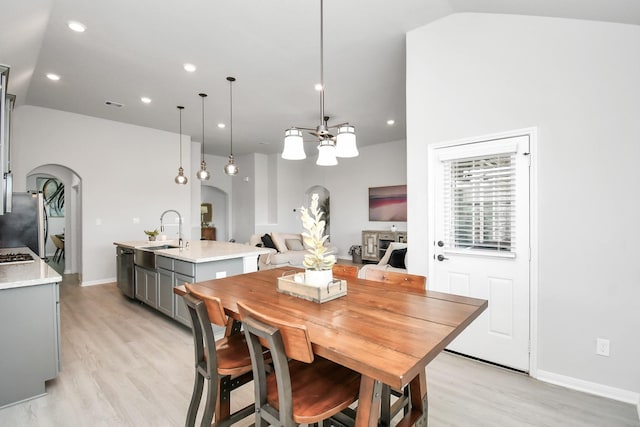 dining area featuring vaulted ceiling, sink, and light hardwood / wood-style floors