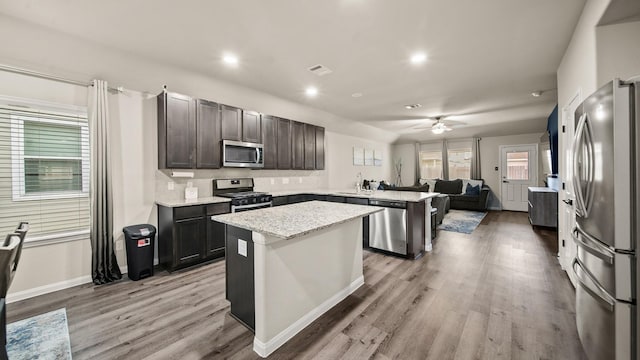 kitchen featuring ceiling fan, a center island, stainless steel appliances, and light wood-type flooring