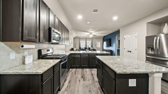 kitchen with appliances with stainless steel finishes, decorative backsplash, sink, light hardwood / wood-style flooring, and kitchen peninsula