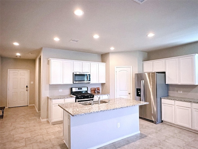 kitchen featuring light stone counters, white cabinets, a center island with sink, and stainless steel appliances