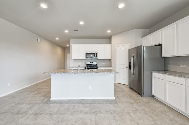 kitchen with light stone counters, stainless steel appliances, and a center island with sink