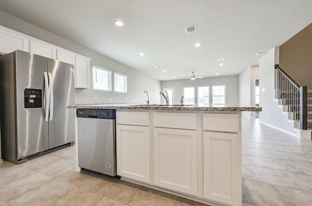 kitchen featuring light stone countertops, white cabinets, appliances with stainless steel finishes, and a kitchen island